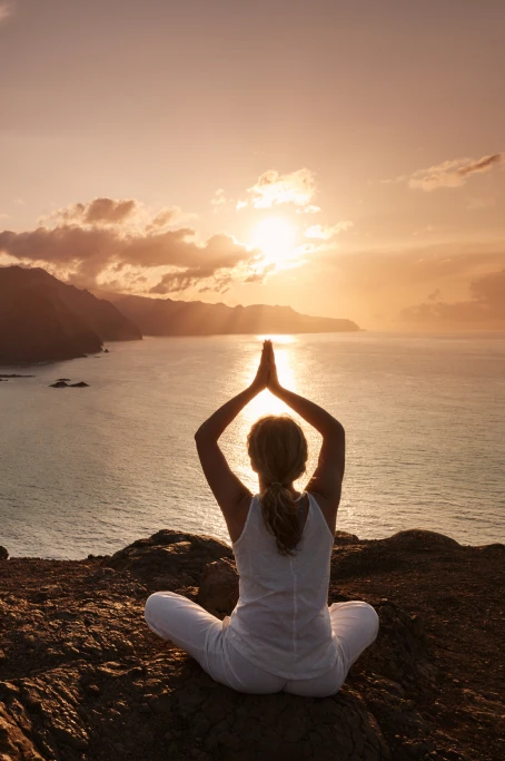 Frau in Yoga-Position vor einem See im Sonnenuntergang